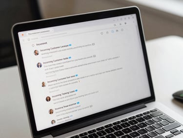 Laptop screen showing a two-way messaging inbox with incoming customer replies and read-receipt indicators, on a clean office desk, overhead studio lighting, tight crop on the screen with reply thread visible