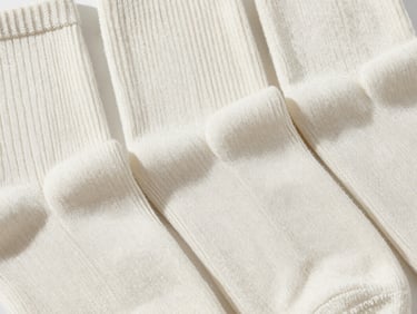 Close-up of finely knit cotton hosiery and socks neatly arranged, highlighting the weave pattern, soft natural shadows