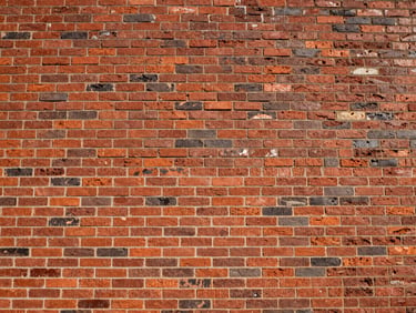 Low-angle shot of a perfectly level red brick facade under hard afternoon sunlight, sharp focus
