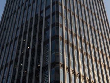 Abstract architectural close-up of a modern steel and glass skyscraper facade, sharp late-afternoon shadows, deep navy tones