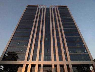 Symmetrical wide-angle architectural shot of a modern glass and steel office tower exterior in Gurgaon, twilight lighting