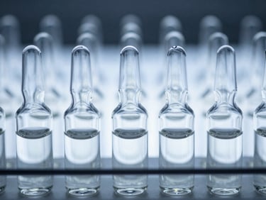 Close-up of sterile borosilicate glass vials arranged in a precise grid under cold blue-white light.