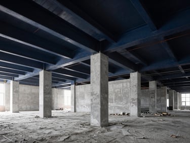 Industrial interior demolition site, clean and organized, dramatic side lighting on concrete dust and steel beams, high contrast architectural construction photography