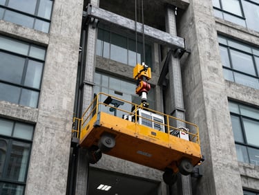 A specialized hydraulic moving elevator in action against modern concrete and glass architecture in Quito, securing heavy equipment during a precise lift, crisp daylight.