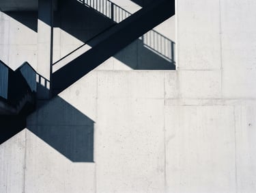 Minimalist architectural photography with sharp diagonal shadows on a clean concrete wall, cool diffused daylight, 35mm