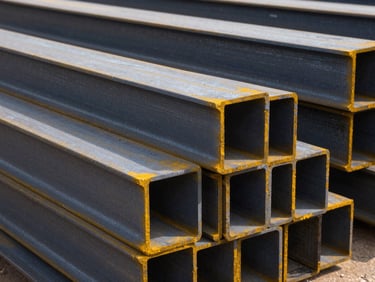 Heavy industrial iron beams stacked in a recycling yard, metallic texture, bright daylight