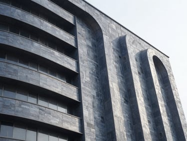 Close-up architectural shot of a factory facade with custom aerodynamic steel curves guiding wind flow, high-contrast technical details, slate gray tones