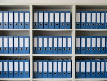 Organized physical archives in a clean corporate storage room, neutral office daylight, structured grid