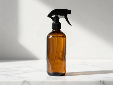 Pristine amber glass spray bottle on a white marble counter, morning light, sharp focus, premium home care.