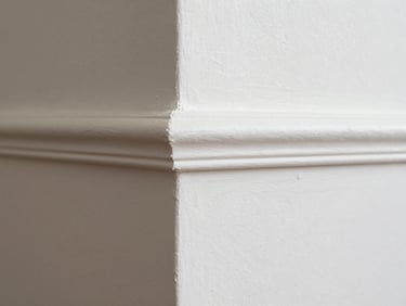 Crisp close-up of a freshly painted interior wall corner showing a clean, straight paint line meeting white skirting board, soft diffused daylight, no brush marks visible, tight framing on the finished edge detail
