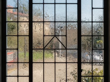 Architectural detail of a decorative glass panel with geometric film pattern, daylight diffracting through the surface showing colour range and film adhesion quality, photographed at medium distance