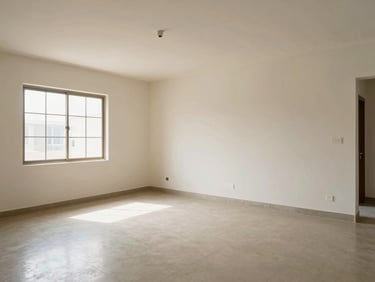Wide environmental shot of a completed 3BHK living room interior in Patna, empty of furniture, showcasing spatial proportion and clean plaster walls under natural window light, tiled floor with precise grout lines, daylight from left