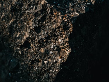 Macro close-up of rough basalt stone texture, dark and moody, side-lit with deep shadows, 35mm film grain.
