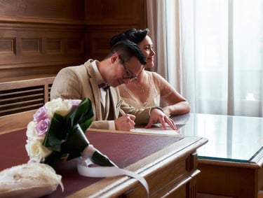Couple de mariés signant leur acte de mariage et un bouquet de fleurs au premier plan.