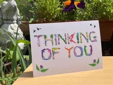 A greeting card with the words Thinking Of You printed in tropical exotic word art