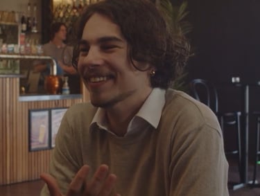 a man sitting at a table with a glass of wine