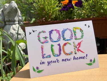 A greeting card with the words Good Luck in you're new home printed in tropical exotic word art