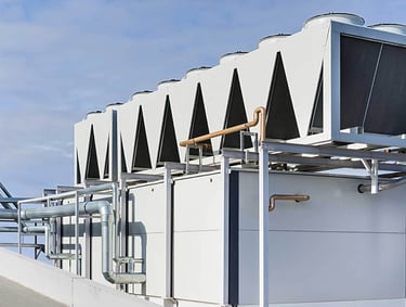 Industrial rooftop HVAC system with air-cooled condensers and water piping.