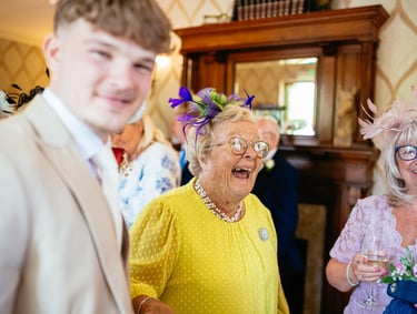 Guests share laughter at a wedding reception in Decourcey’s Manor, Cardiff, full of colour, joy and character.