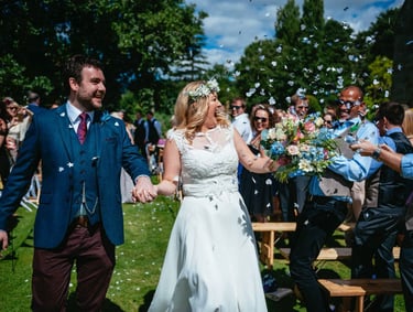 Confetti joy as the couple walk hand in hand at Brinsop Court Manor House and Barn, surrounded by smiling guests.