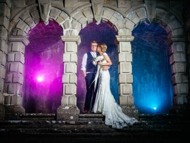 a bride and groom standing in front of a castle