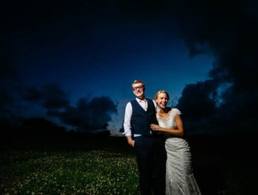 a bride and groom standing in a field at night