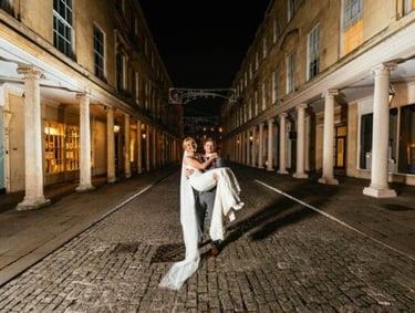 Groom carrying bride at night on cobbled street in Bath city centre, captured by wedding photographer Owen Mathias