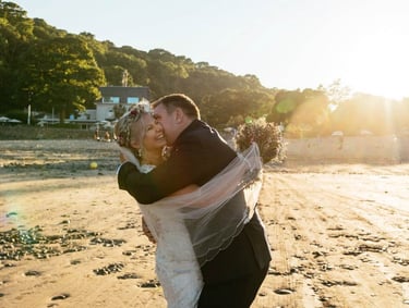 a bride and groom kissing on the beach