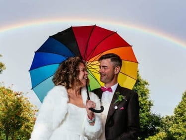 a bride and groom standing under a rainbow - colored rainbow - colored rainbow - colored