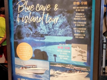The picture shows a billboard advertising a one-day boat visit to the Blue Cave on the island of Biševo.