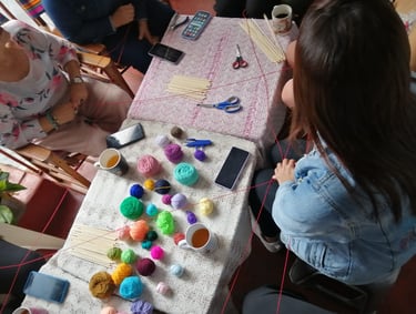 Grupo de personas en taller de tejido de mandalas, con hilos de colores y bebidas calientes