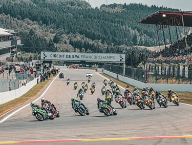Des pilotes de moto en pleine course sur un circuit, avec un public en arrière-plan