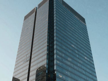 Sharp photography of a modern glass skyscraper corner against a clear pale blue sky, North American / US city, emphasizing geometric precision and sophisticated engineering.