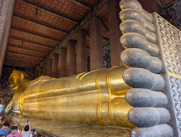 The giant gold Reclining Buddha statue at Wat Pho temple in Bangkok showing intricate mother-of-pearl feet.