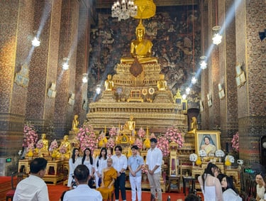 Visitors posing with a monk inside Wat Phra Chetuphon (Wat Pho) temple in Bangkok, Thailand.