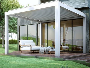 Modern white aluminum louvered pergola over a wooden deck with outdoor lounge furniture and green lawn.