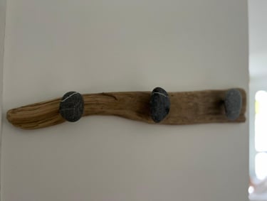 Rustic wall-mounted coat rack made of natural driftwood with smooth stone hooks.