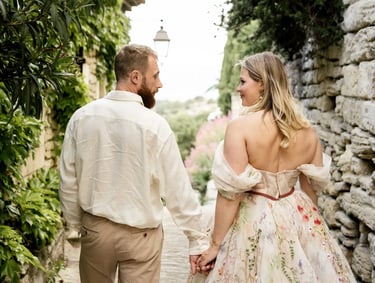 Couple walking hand in hand, looking at each other — woman in floral dress, Provence couple session