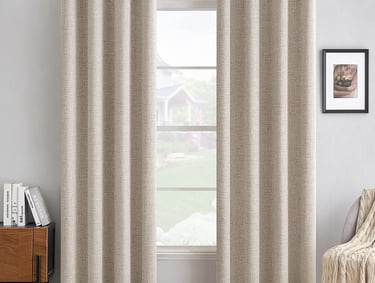 Beige grommet blackout curtains with a linen texture hanging in a bright modern living room.