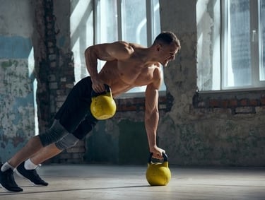 A shirtless muscular man performing a kettlebell renegade row in a rustic gym setting.