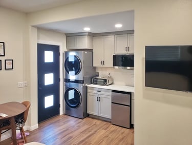 Black door in kitchenette with light blue cabinets and stainless steel appliances.