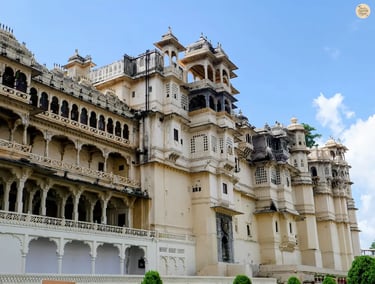 Facade of Udaipur City Palace viewed from Manek Chowk, showing domes, arches, and white marble walls.