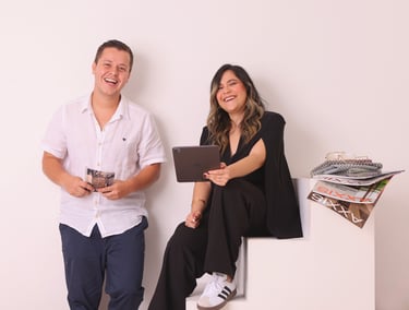 a man and woman sitting on a white cube