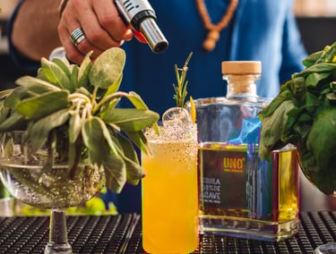 a man is making a uno tequila cocktail at a bar with a bottle of uno tequila añejo