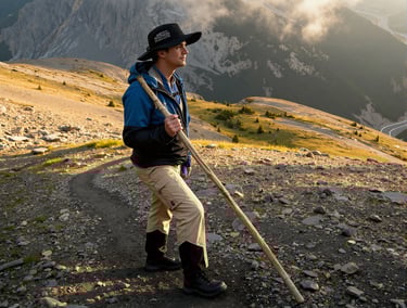 a man wearing a hat hiking up a mountain trail