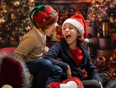 2 boys sitting on a couch in a christmas tree