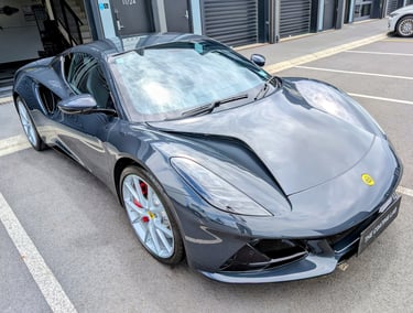 A grey Lotus Emira sports car with ceramic coating parked in a lot outside The Coating Lab