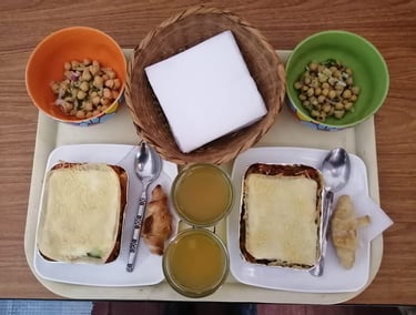 Bandeja con almuerzo, lasaña con minicroisant, ensalada y limonada con cubiertos y servilletas
