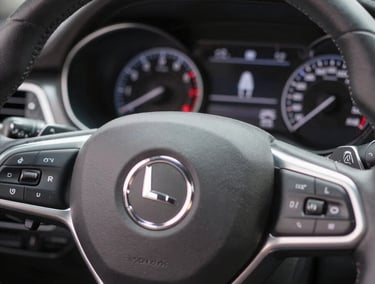 A close-up of a clean modern car dashboard with illuminated dials and steering wheel, soft natural light, crisp automotive photography, professional editorial style, 50mm lens