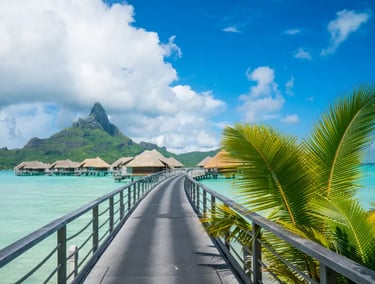 Luxury overwater bungalows in Bora Bora with a walkway over turquoise water and Mount Otemanu view.
